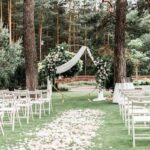 plenerowy ślub w ogrodzie, plenerowa ceremonia ślubu, białe krzesła, piękne dekoracje